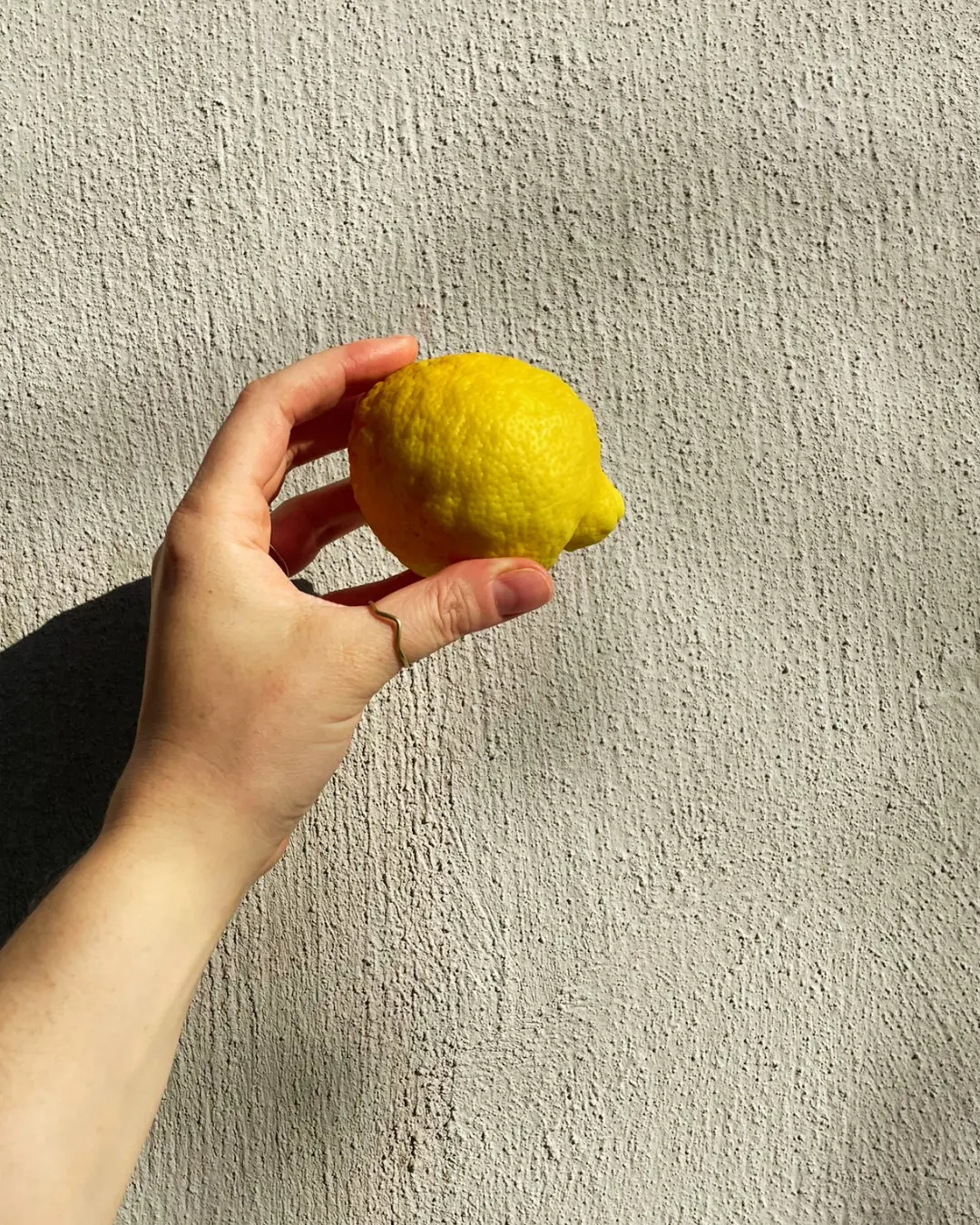 A hand holding a fresh lemon in the sunshine